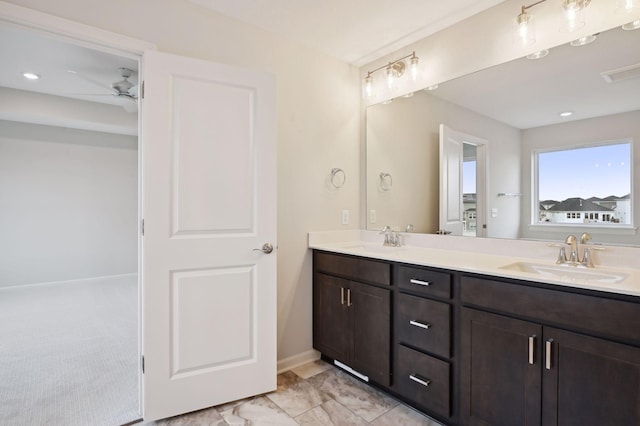 full bath with double vanity, a ceiling fan, baseboards, and a sink