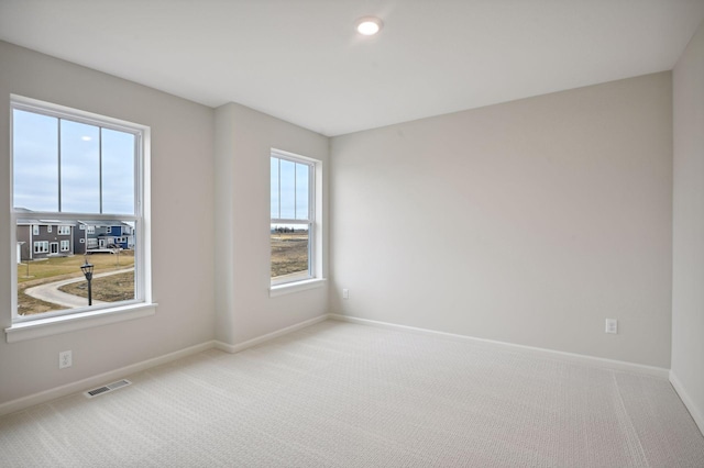 carpeted empty room featuring baseboards and visible vents