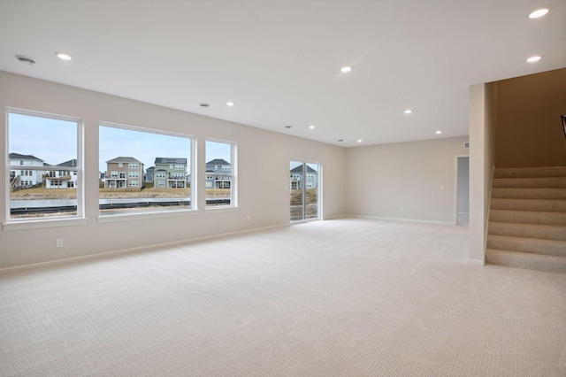 unfurnished living room with recessed lighting, stairs, baseboards, and light colored carpet