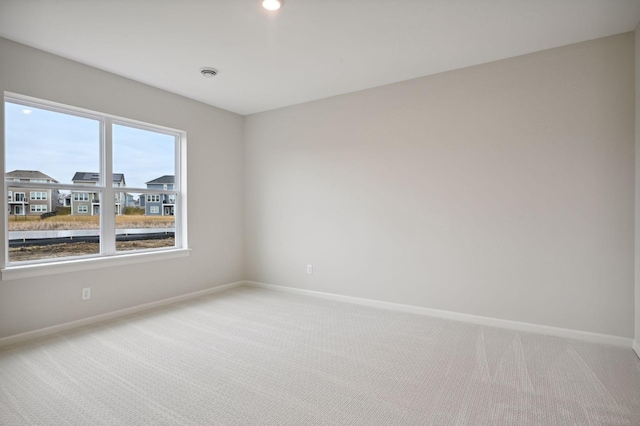 carpeted spare room featuring baseboards