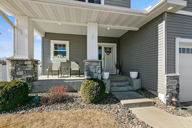 property entrance featuring a garage, stone siding, and a porch