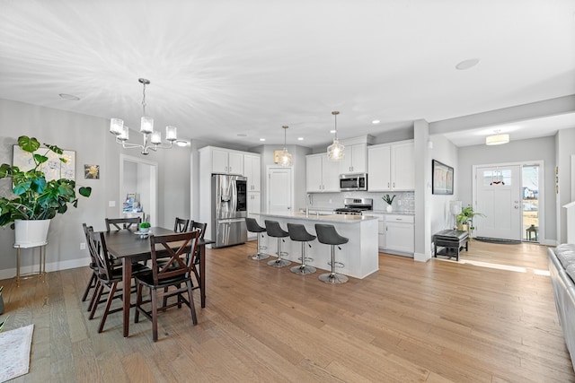 dining area with a chandelier, recessed lighting, light wood-style flooring, and baseboards