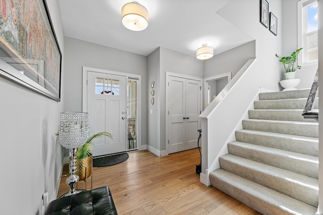 entryway featuring baseboards, stairway, and wood finished floors