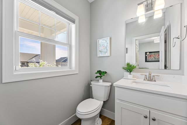 bathroom with toilet, baseboards, wood finished floors, and vanity