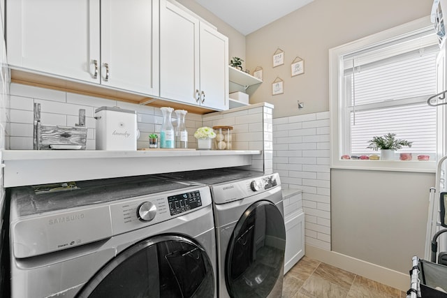 clothes washing area with cabinet space, baseboards, tile walls, and washer and dryer