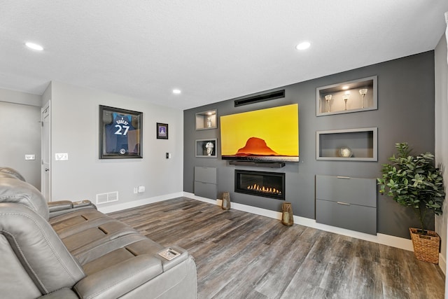 living room with recessed lighting, baseboards, wood finished floors, and a glass covered fireplace