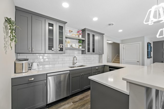 kitchen featuring a peninsula, a sink, stainless steel dishwasher, gray cabinets, and open shelves