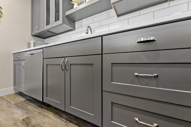 interior space with baseboards, dark wood finished floors, gray cabinets, stainless steel dishwasher, and backsplash