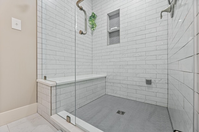 bathroom with a shower stall and baseboards