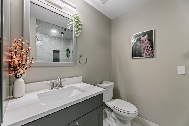 bathroom with baseboards, a tile shower, vanity, and toilet