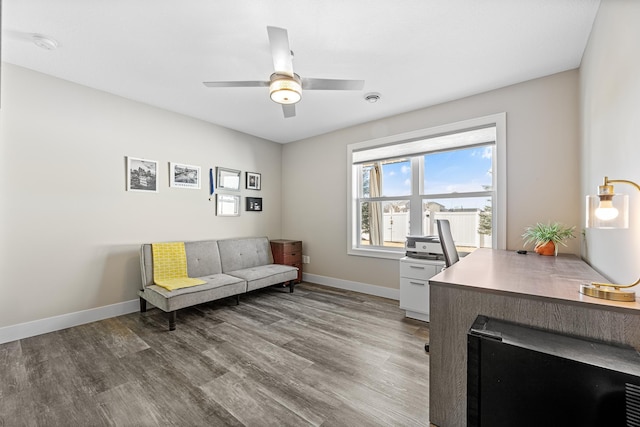 interior space featuring a ceiling fan, baseboards, and wood finished floors