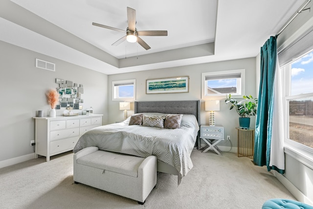 bedroom with light carpet, a raised ceiling, visible vents, and baseboards