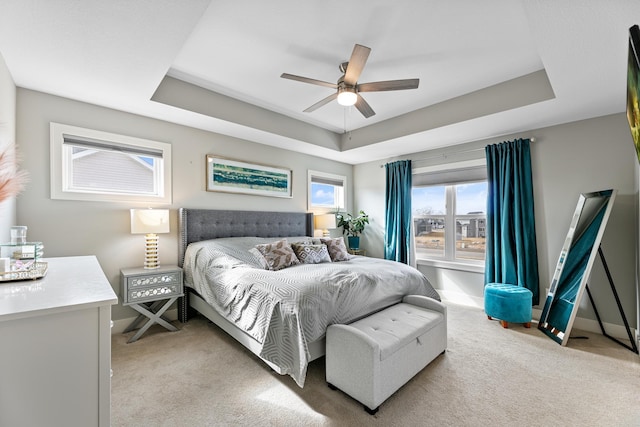 bedroom with light carpet, baseboards, and a tray ceiling