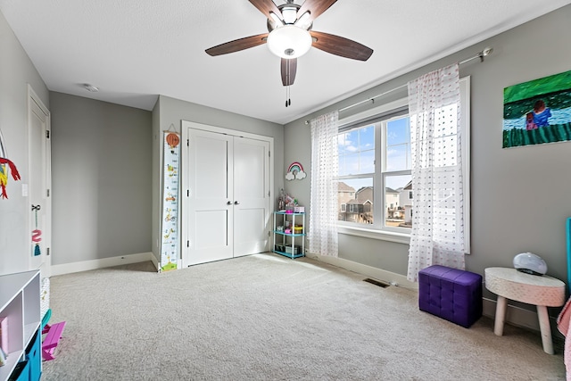 recreation room with carpet floors, a textured ceiling, baseboards, and a ceiling fan