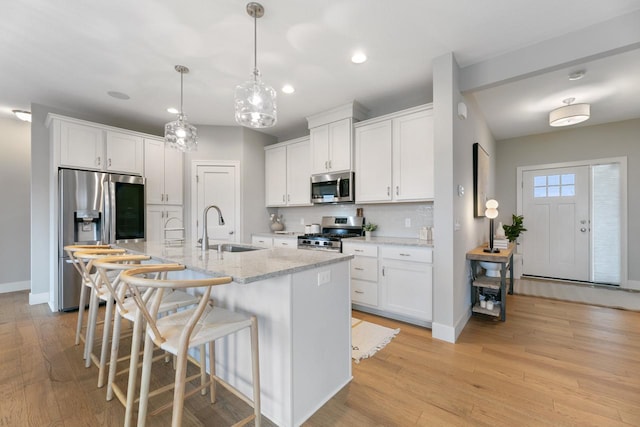 kitchen with a breakfast bar area, tasteful backsplash, white cabinetry, a sink, and stainless steel appliances