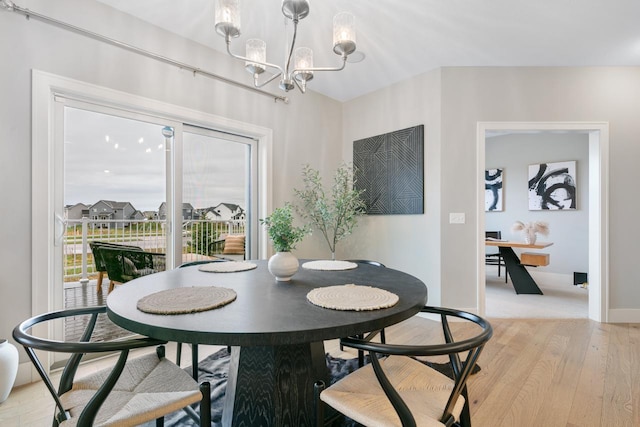 dining space featuring light wood finished floors, a chandelier, and baseboards
