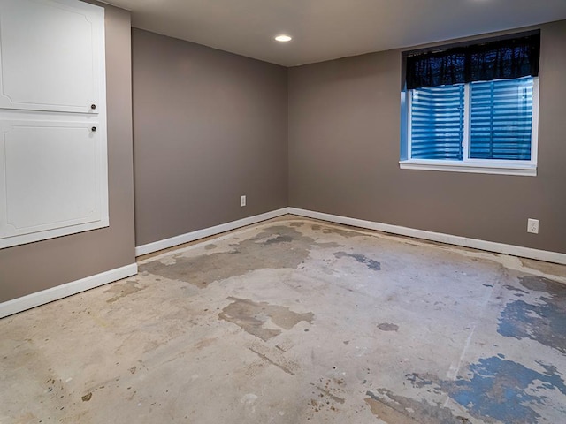 spare room featuring unfinished concrete flooring and baseboards