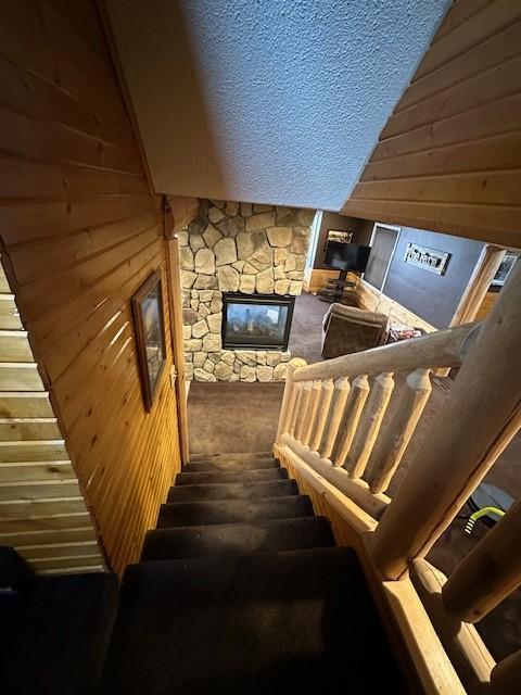 1344 385th Ave, Ten Mile Lake Twp, MN 56218 - staircase featuring a fireplace, wooden walls, vaulted ceiling, and a textured ceiling