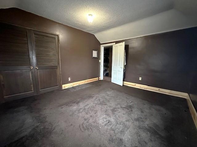 1344 385th Ave, Ten Mile Lake Twp, MN 56218 - unfurnished bedroom featuring vaulted ceiling, baseboards, multiple closets, carpet flooring, and a textured ceiling