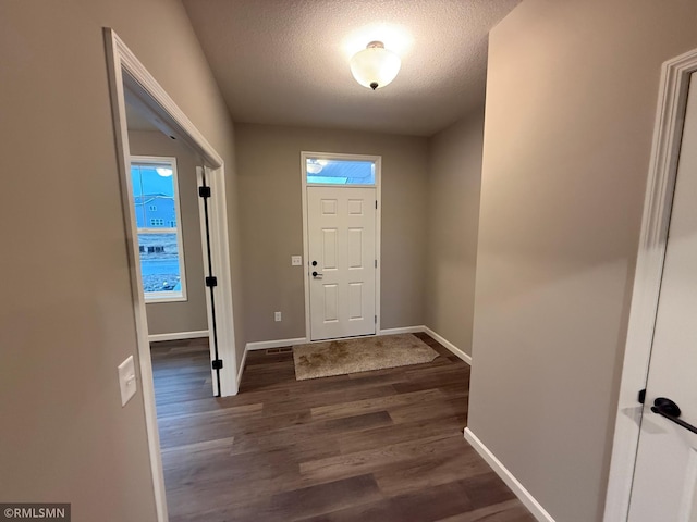 entrance foyer with dark wood-type flooring, a textured ceiling, and baseboards