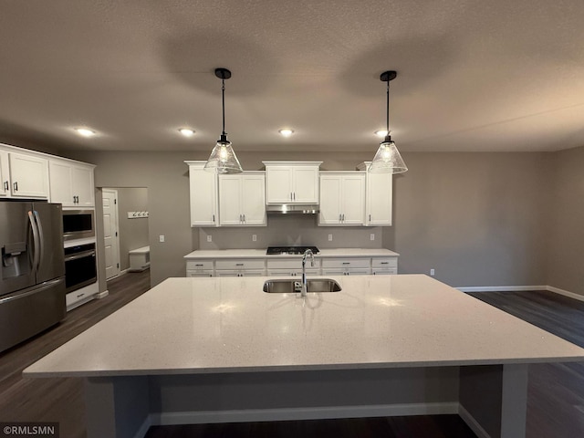 kitchen with stainless steel appliances, a spacious island, a sink, white cabinetry, and dark wood finished floors