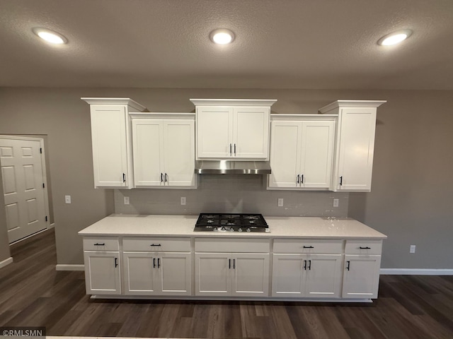 kitchen featuring dark wood-style floors, stainless steel gas cooktop, light countertops, under cabinet range hood, and white cabinetry