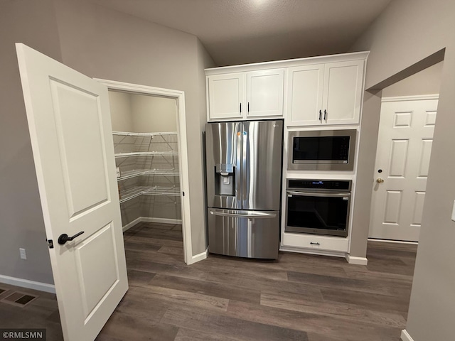 kitchen with stainless steel appliances, visible vents, white cabinetry, baseboards, and dark wood-style floors