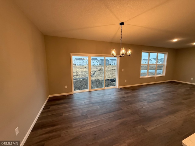 unfurnished dining area with baseboards, a chandelier, and dark wood-style flooring