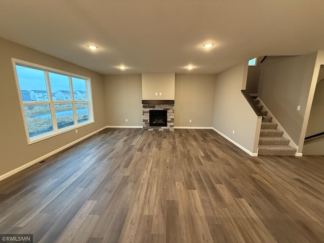 unfurnished living room with stairway, dark wood-style flooring, and baseboards