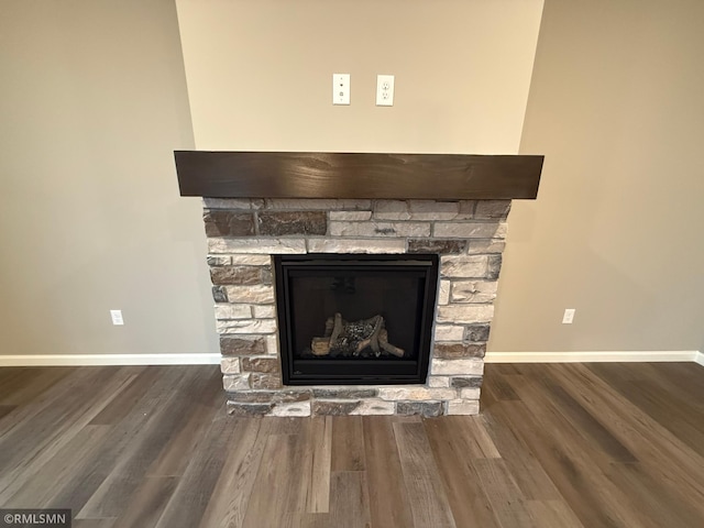 interior details with a stone fireplace, baseboards, and wood finished floors