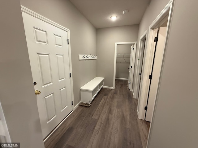 hall featuring dark wood-type flooring and baseboards