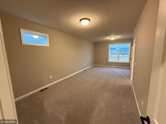 unfurnished room featuring carpet floors, visible vents, a textured ceiling, and baseboards