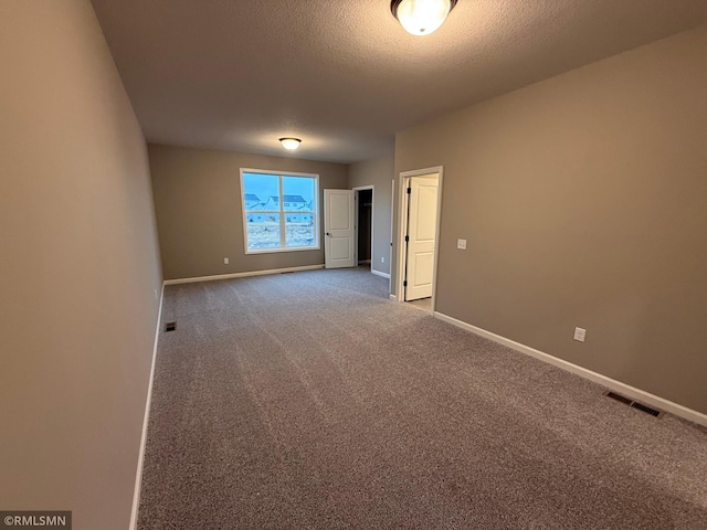 carpeted empty room with visible vents, a textured ceiling, and baseboards