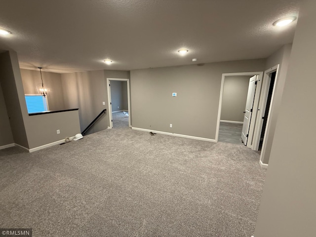 unfurnished room with a textured ceiling, carpet floors, and baseboards