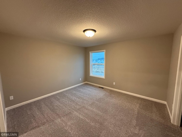 spare room with carpet floors, visible vents, baseboards, and a textured ceiling