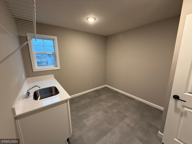 washroom with a textured ceiling, a sink, and baseboards