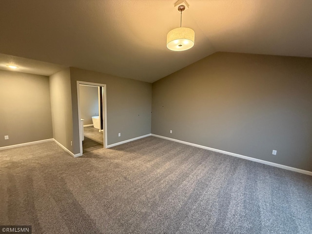 spare room featuring lofted ceiling, carpet, and baseboards