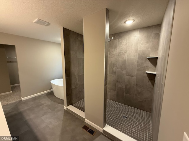 bathroom with visible vents, baseboards, walk in shower, a textured ceiling, and a freestanding tub