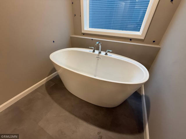 full bath with baseboards and a freestanding bath