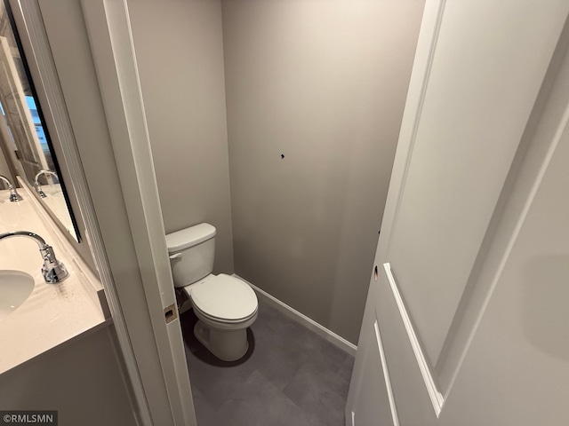 bathroom featuring baseboards, a sink, toilet, and double vanity