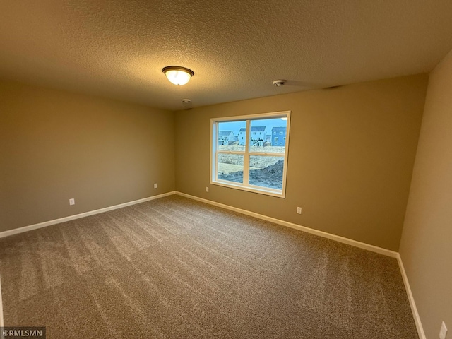 unfurnished room with a textured ceiling, carpet, and baseboards