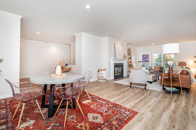 2501 30th Ave S Unit 102, Fargo, ND 58103 - dining room with light wood-style floors, a glass covered fireplace, a textured ceiling, recessed lighting, and baseboards