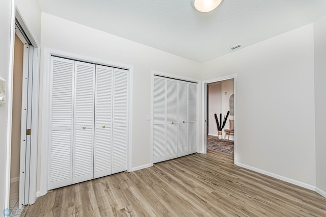2501 30th Ave S Unit 102, Fargo, ND 58103 - unfurnished bedroom featuring light wood-type flooring, baseboards, and multiple closets
