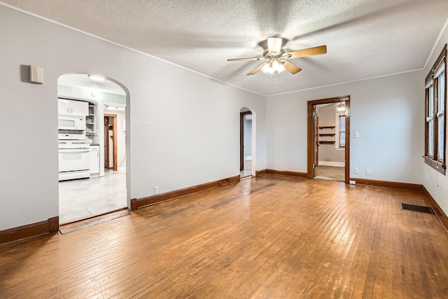 spare room with light wood-type flooring, arched walkways, and visible vents