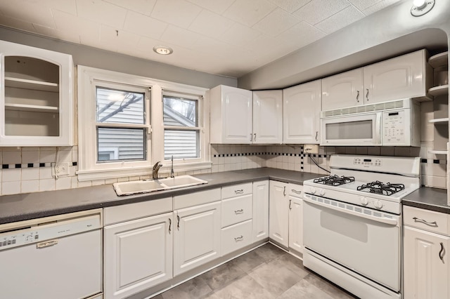 kitchen featuring dark countertops, white appliances, white cabinetry, and a sink