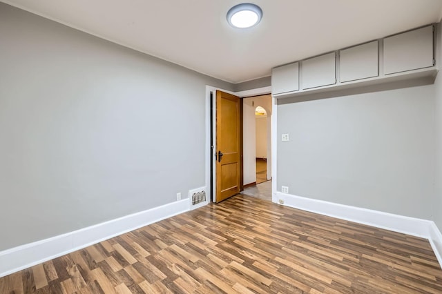 spare room featuring visible vents, baseboards, and wood finished floors