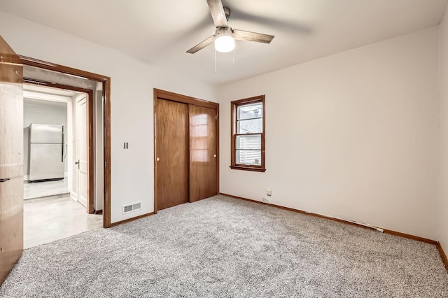 unfurnished bedroom featuring light carpet, visible vents, baseboards, a closet, and freestanding refrigerator