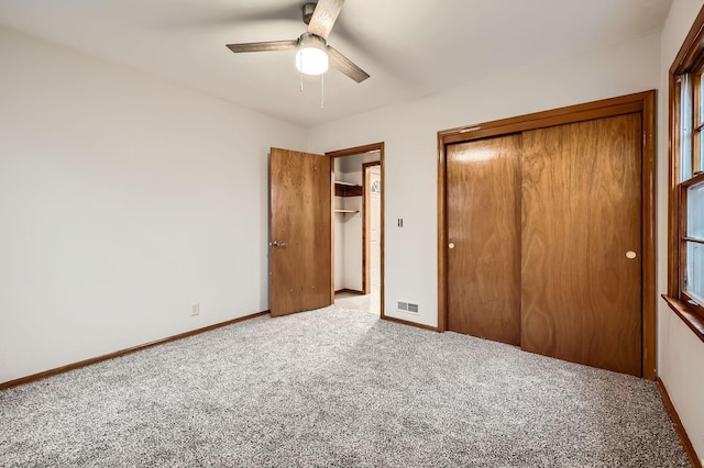 unfurnished bedroom featuring baseboards, carpet flooring, visible vents, and multiple closets