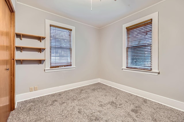 carpeted empty room featuring baseboards and crown molding