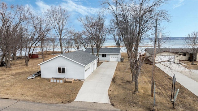 exterior space featuring a garage, concrete driveway, roof with shingles, and an outdoor structure